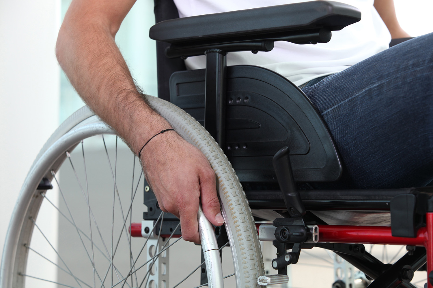 Closeup of a man's hand on the wheel of his wheelchair